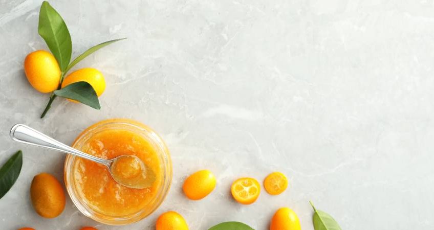 Marmellata di kumquat in un vasetto con frutti di kumquat sparsi