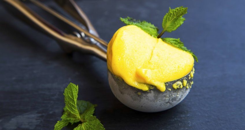 Sorbetto al mango servito in un cucchiaio da gelato